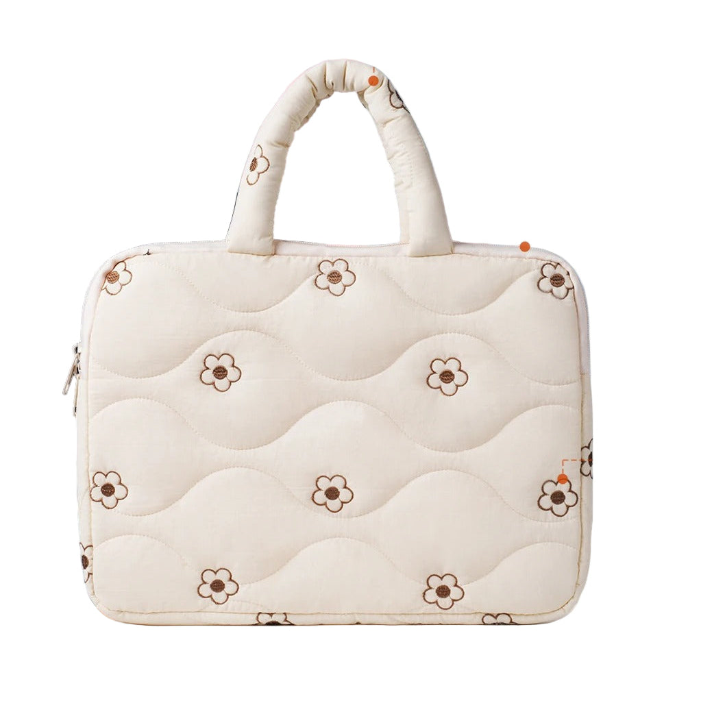 White quilted laptop bag with floral patterns on a blurred office background